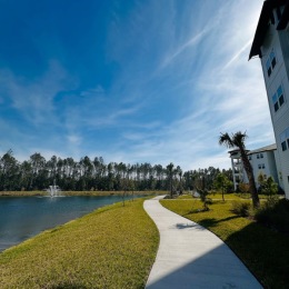 walkway between a building and a lake with grass