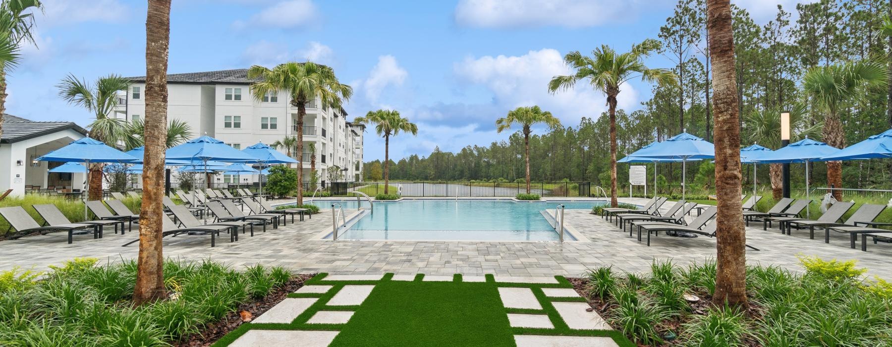 a pool with palm trees and a building in the background